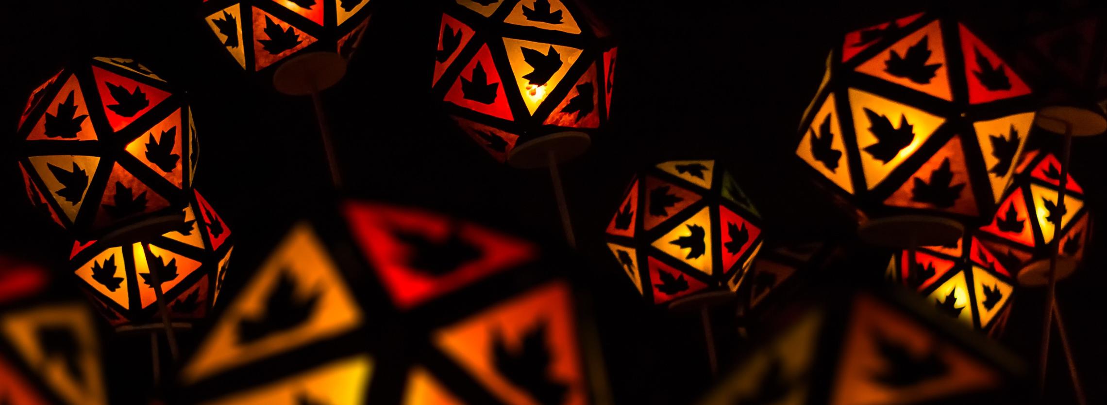 Bunte Laternen in warmen Rot- und Orangetönen mit Blattmotiven in einer dunklen Nacht