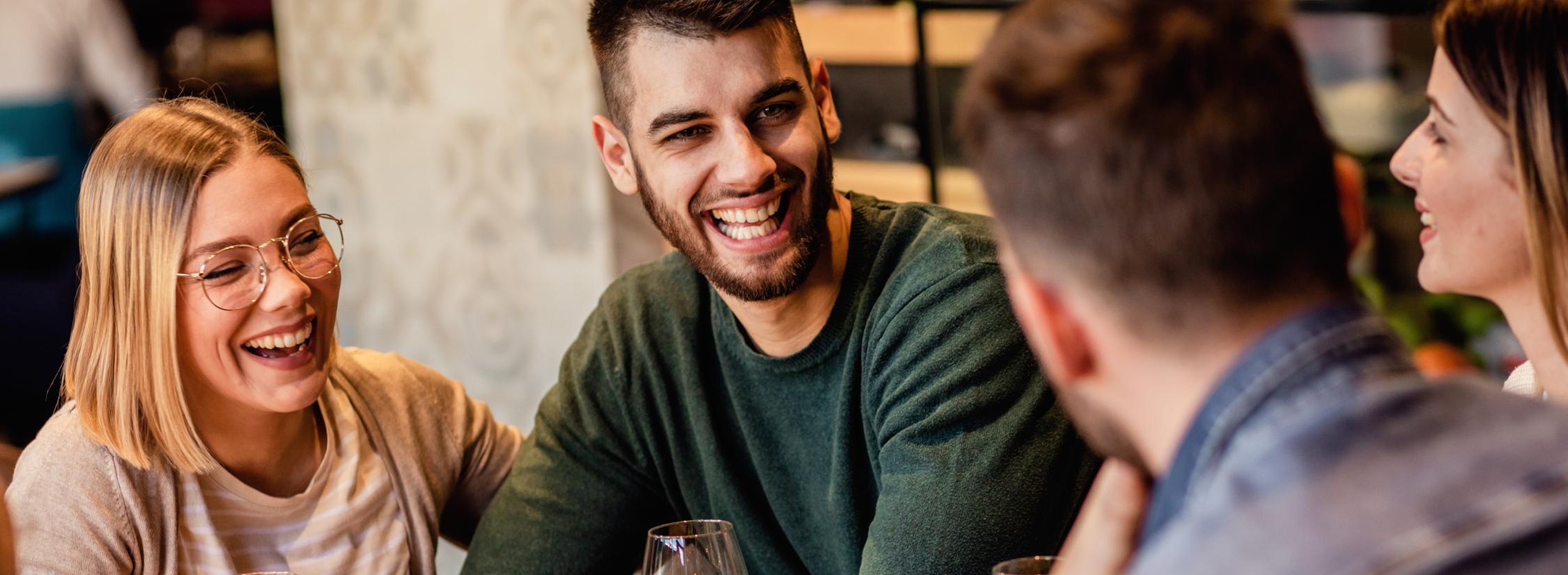 Junge Leute, die sich mit Freude bei einem Glas Wein und Imbiss unterhalten