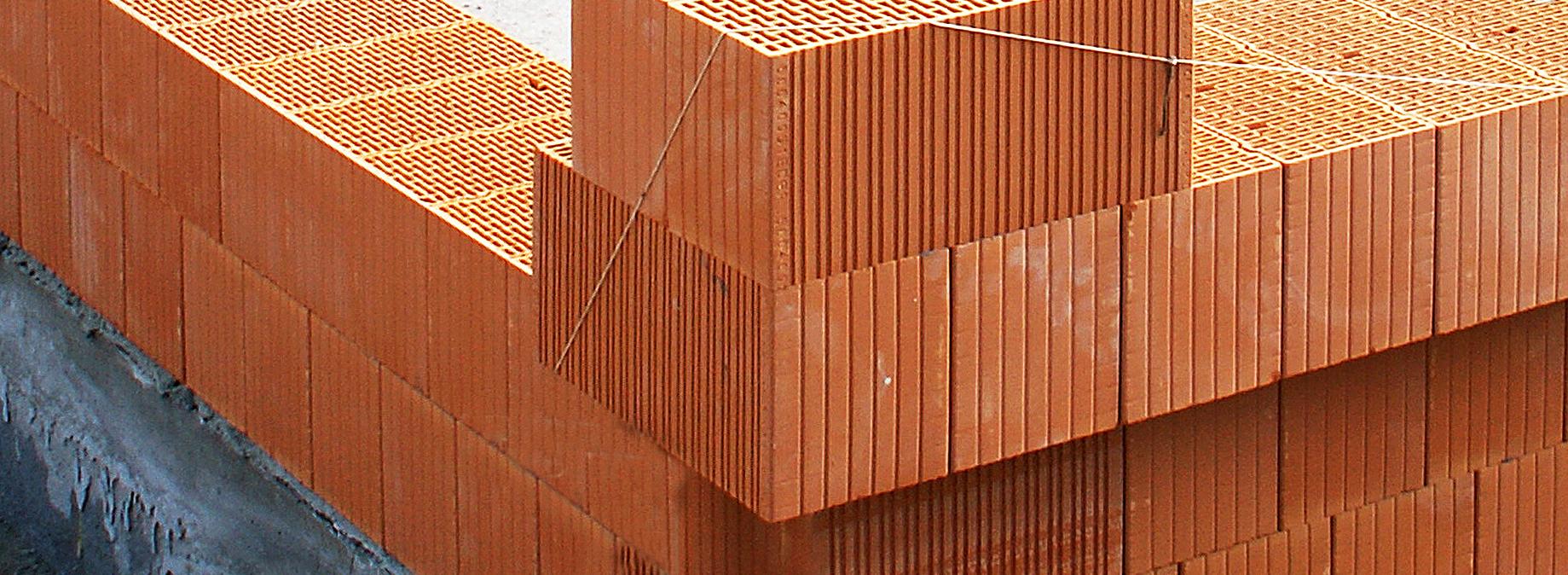 Ecke eines Rohbaus mit roten Ziegeln auf Betonsockel