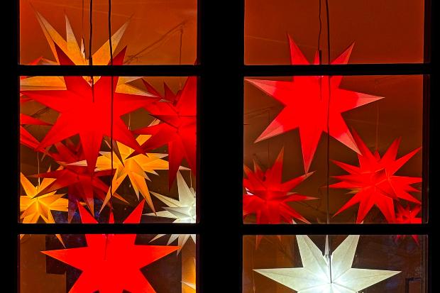 Fenster mit leuchtenen Papiersternen dahinter