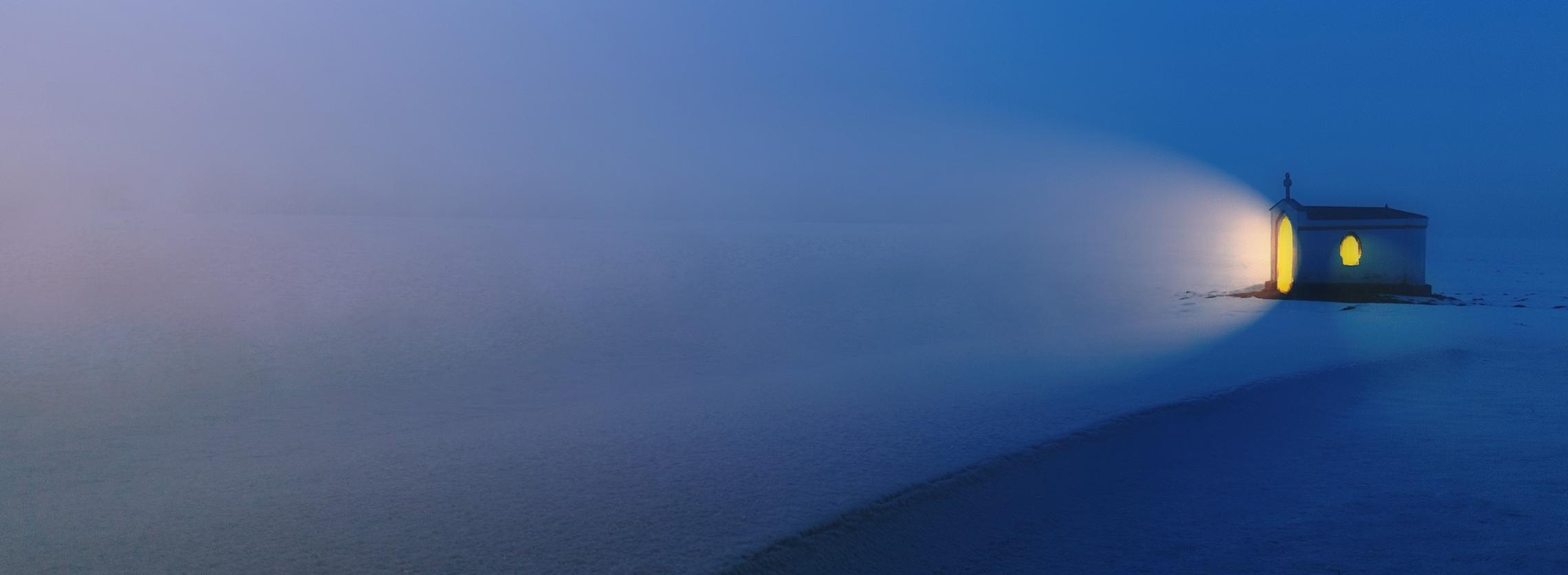 Kleine, einsame Kapelle leuchtet in abendlicher Schneelandschaft
