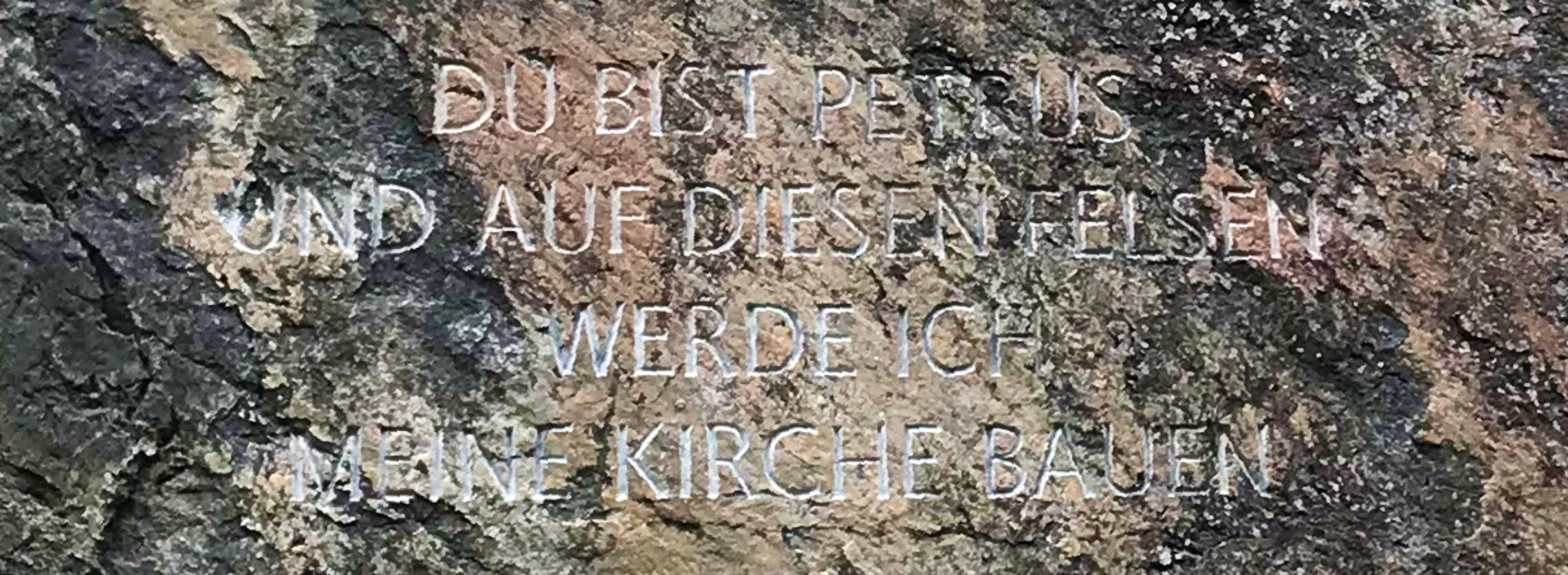 Fels mit Inschrift: Du bist Petrus – der Fels – und auf diesen Felsen werde ich meine Kirche bauen