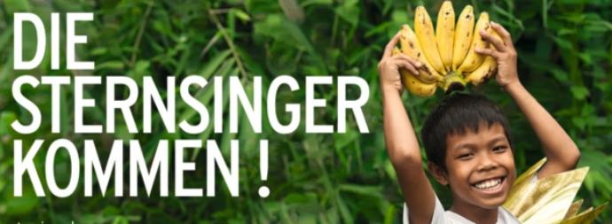 Banner 'Die Sternsinger kommen' mit Jungen, der Bananen auf dem Kopf festhält, die so wie eine Krone aussehen