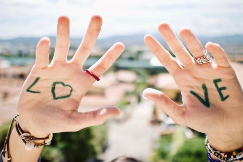 In die Luft gestreckte Hände, auf einer steht LO auf der anderen VE (nebeneinander zusammen LOVE)