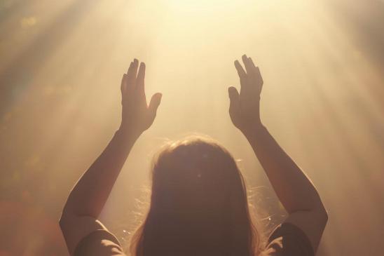 Hände, die einem von oben kommenden, goldenen Licht entgegengestreckt werden