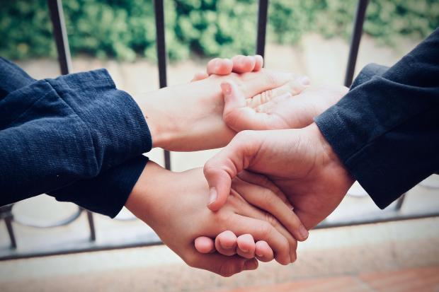 Zwei Jungen, die sich mit verkreuzten Armen beide Hände reichen