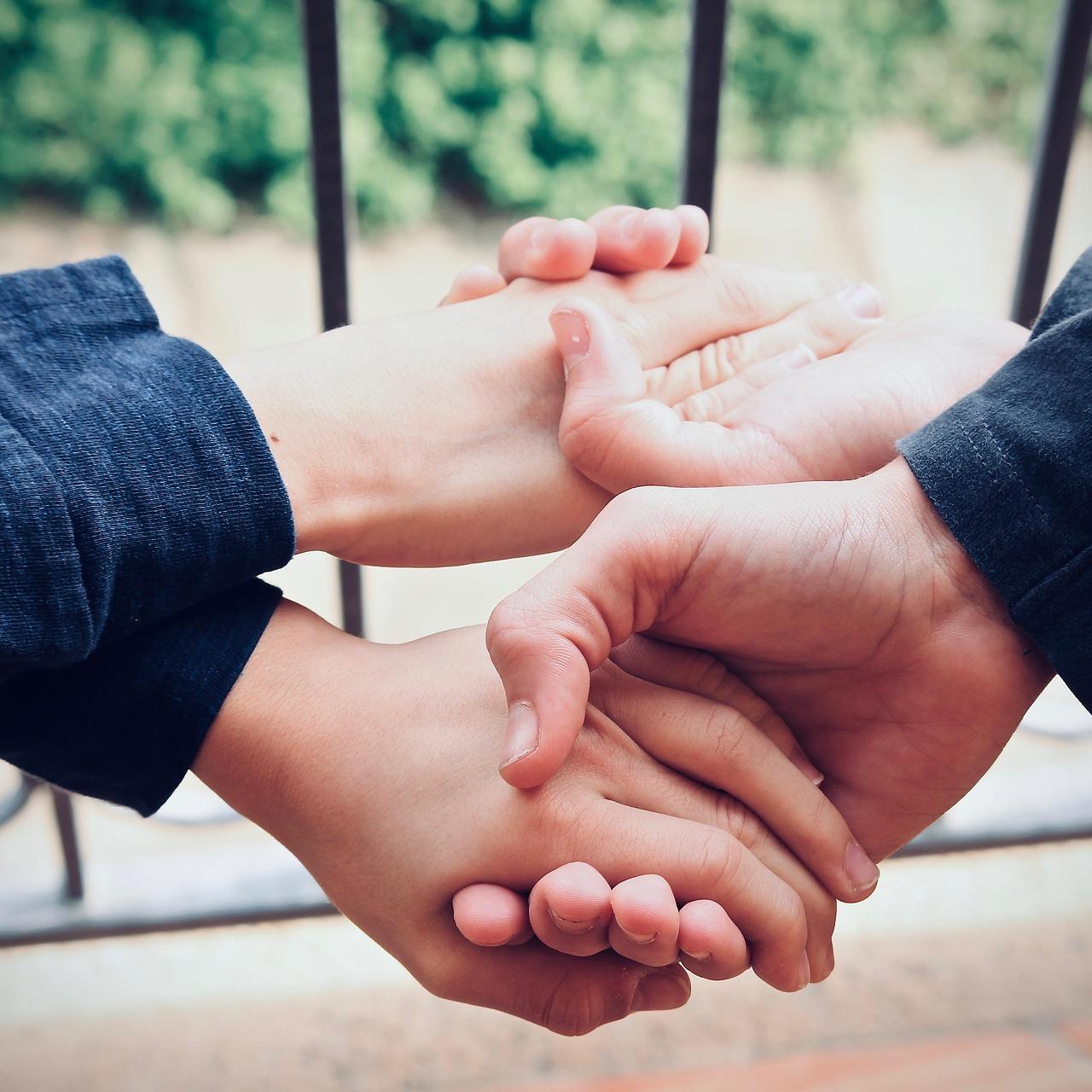 Zwei Jungen, die sich mit verkreuzten Armen beide Hände reichen