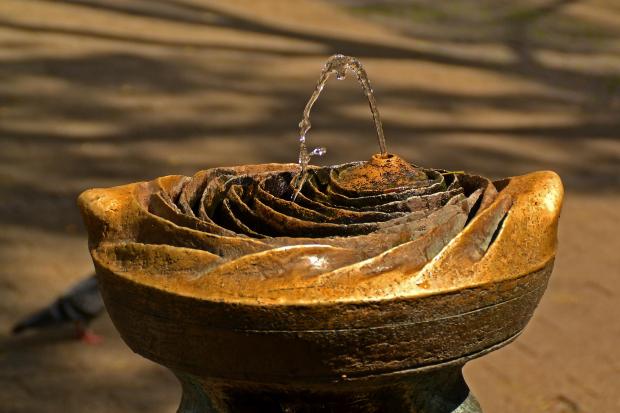 Dekorativer Brunnen aus Bronze, der wie eine stilisierte Rose geformt ist und aus dessen Mitte ein Wasserstrahl austritt
